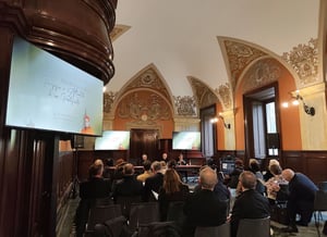 Sala conferenze affrescata durante l’evento “Che fine hanno fatto i ‘poveri pazzerelli’?”, con il pubblico seduto e i relatori al tavolo, affiancati da monitor che mostrano il titolo dell’incontro