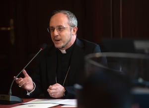 Mons. Flavio Pace interviene alla conferenza parlando al microfono e gesticolando con la mano destra.