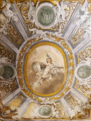 Affresco su volta con al centro una figura femminile allegorica seduta, coronata e con scudo e scettro, incorniciata da ghirlande dorate. Attorno, numerosi putti bianchi in rilievo e quattro medaglioni verdi con scene mitologiche e guerriere